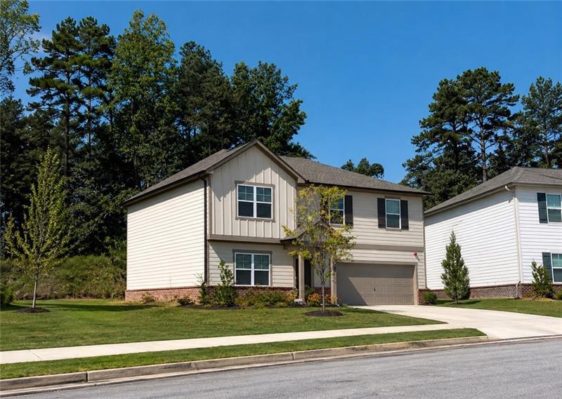 Two-story home with a two-car garage, light-colored siding, dark shutters, and a well-maintained lawn