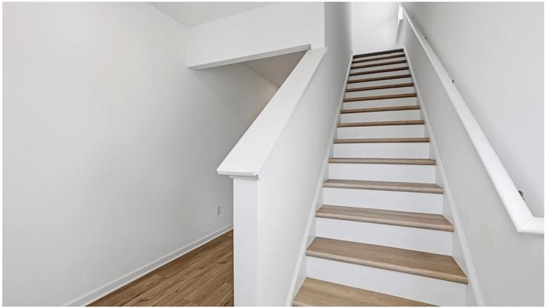 Stairway with wood finished floors and baseboards